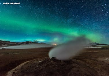 Northern Lights and a starry sky over a steam vent in a geothermal area near Lake Mývatn