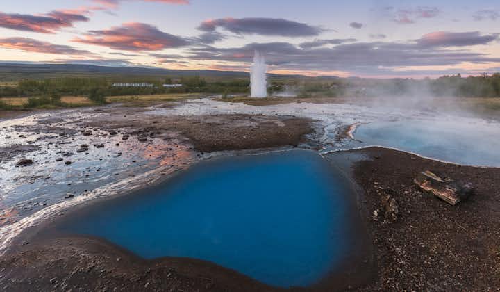 The geyser Strokkur in front of azure coloured fumaroles in the geothermal valley Haukadalur in South Iceland.