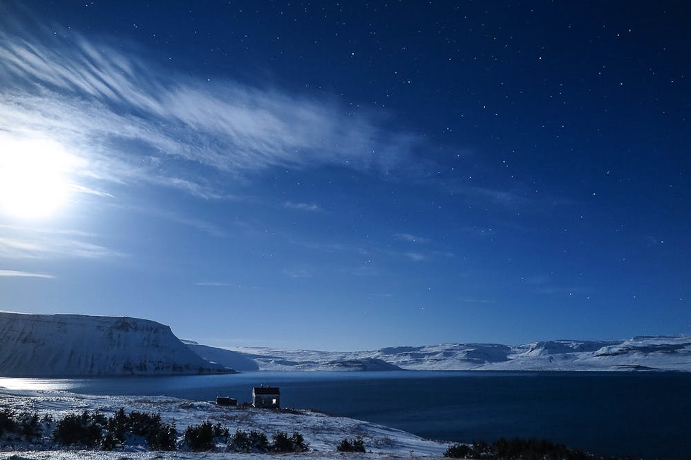 A stunning sky with the midnight sun and stars over the Westfjords in summer.