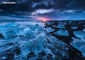 Auf einer Mietwagen-Winterreise kannst du den Diamantstrand am Abend besuchen und zuschauen, wie die Sonne zwischen den glitzernden Eisbergen untergeht.