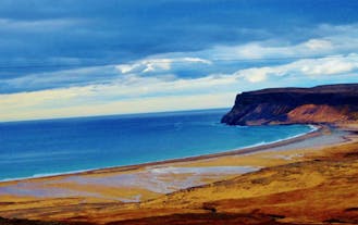 Het blauw van de oceaan contrasteert met het gouden strand Raudasandur in de zuidelijke Westfjorden van IJsland.