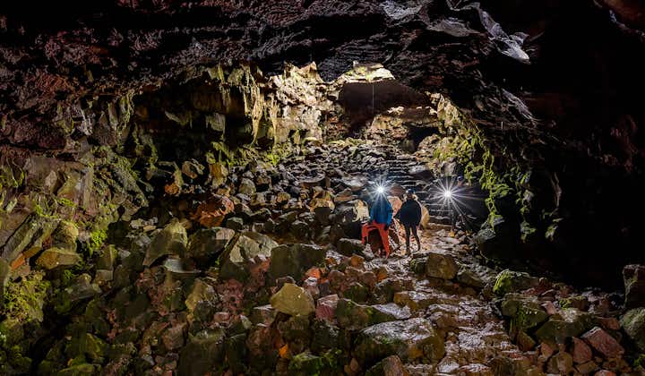 Two people explore the underground world of a lava tunnel.