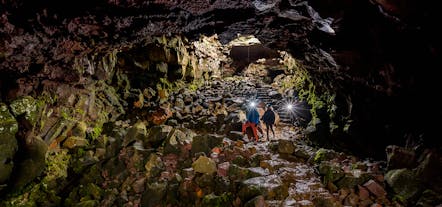Two people explore the underground world of a lava tunnel.
