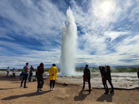 A group of travelers admiring the spouting geyser Strokkur on a Golden Circle tour.