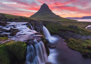 La montagna Kirkjufell a forma di punta di freccia nella penisola di Snæfellsnes, bagnata dai raggi del sole di mezzanotte.
