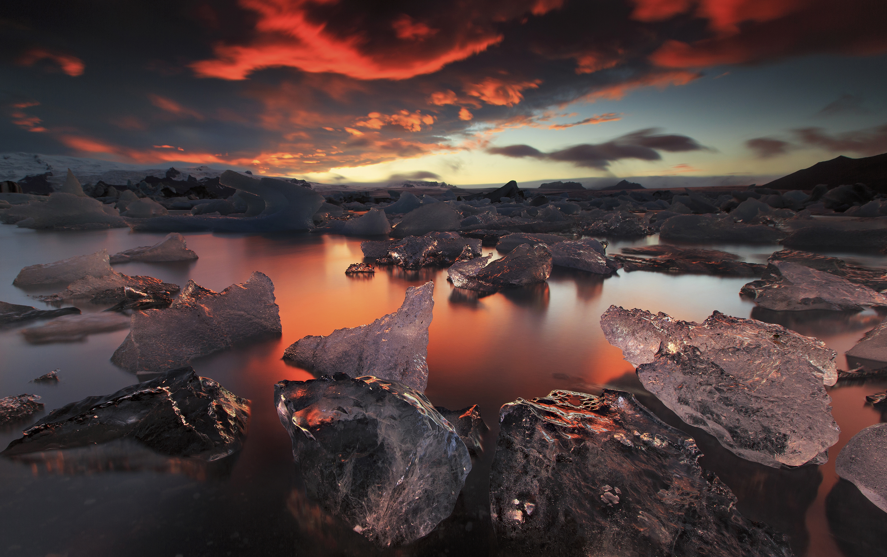 夕暮れの太陽とヨークルスアゥルロゥン氷河湖
