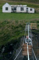 A traveller in Iceland is hand-pulled across a glacial river in a cableway cart