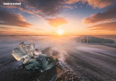 Isen smälter medan solen går ner över Diamond Beach i Vatnajökull nationalpark.