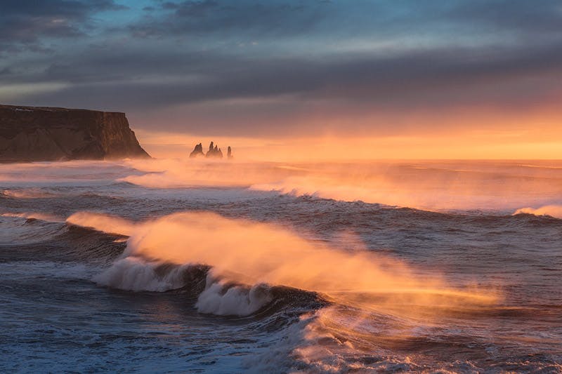 Reynisdrangar rock stacks in the far distance, as the sea crashes upon the shore.