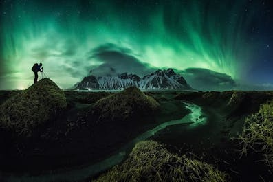 Vestrahorn mountain during the winter months, with aurora dancing above.