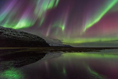 Les aurores boréales étincelantes dansent au-dessus des fjords de l'Est montagneux.