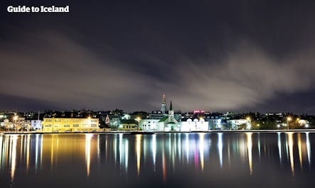 The city lights of Reykjavik reflect in the water.