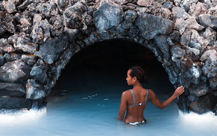 Eine Frau badet im Wasser des Geothermalbads Blaue Lagune.