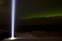 Northern Lights dancing alongside the beam of the Imagine Peace Tower.