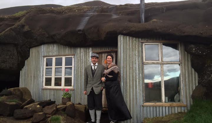 A couple in traditional clothing outside the Laugarvatnshellar cave house.