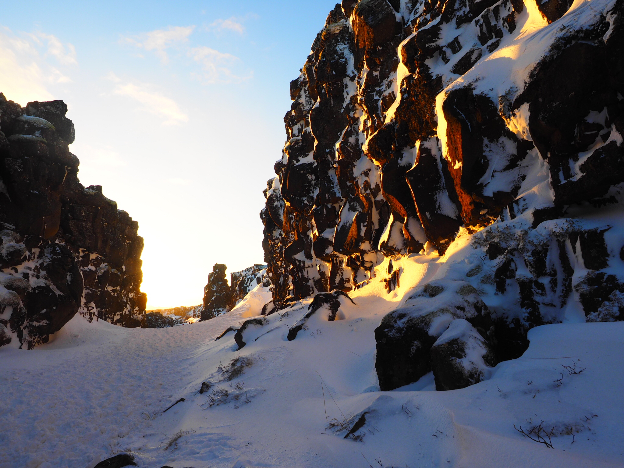 Sun beams down on snowy rock formations in a gorge in Þingvellir