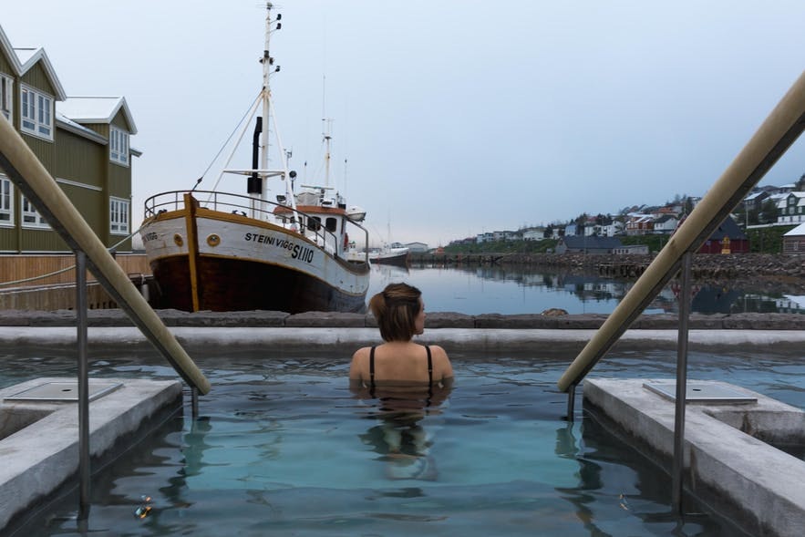 在冰岛锡格吕菲厄泽的温泉泳池中放松身心，体验冰岛峡湾小镇的避世风情