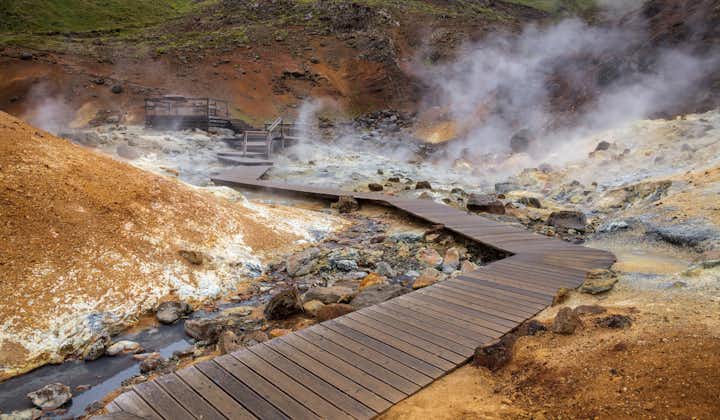 Steam rises from the ground amid wooden walkways in the Seltun geothermal area.