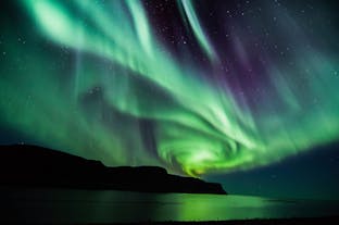 Spektakularna zielona zorza polarna nad jeziorem w Islandii