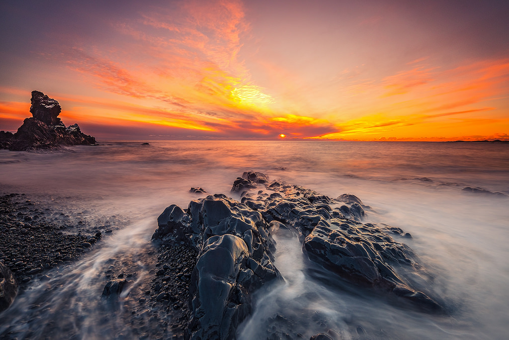 Shades of pink and orange fill the sky as the sun sets over the dramatic coastline of the Snæfellsnes peninsula.