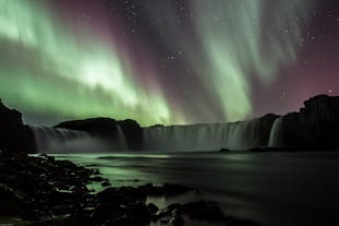 The northern lights dance over Godafoss waterfall.