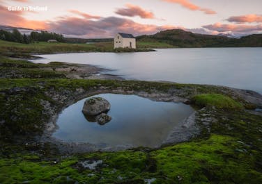 An old house stands by the banks of Lagarfljót river in east Iceland, on a peaceful summer evening.