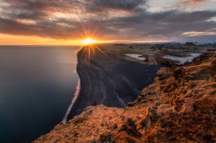 Solen går ner över den ändlösa svarta sanden på Islands sydkust.