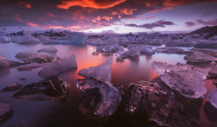 Glittering icebergs serenely drifting on Jökulsárlón glacier lagoon at sunset.