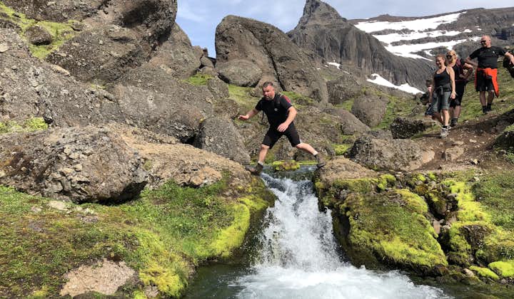 A man jumping over a brook in the east highlands, near Borgarfjörður eystri, iceland.