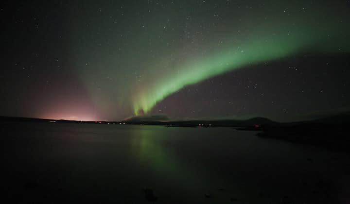 A blaze of green and pink northern lights forming int he sky.
