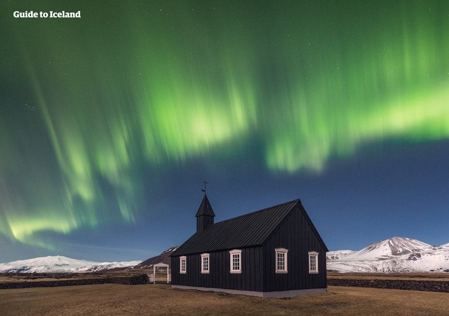 A windswept church under the northern lights, before Snæfellsjökull glacier.