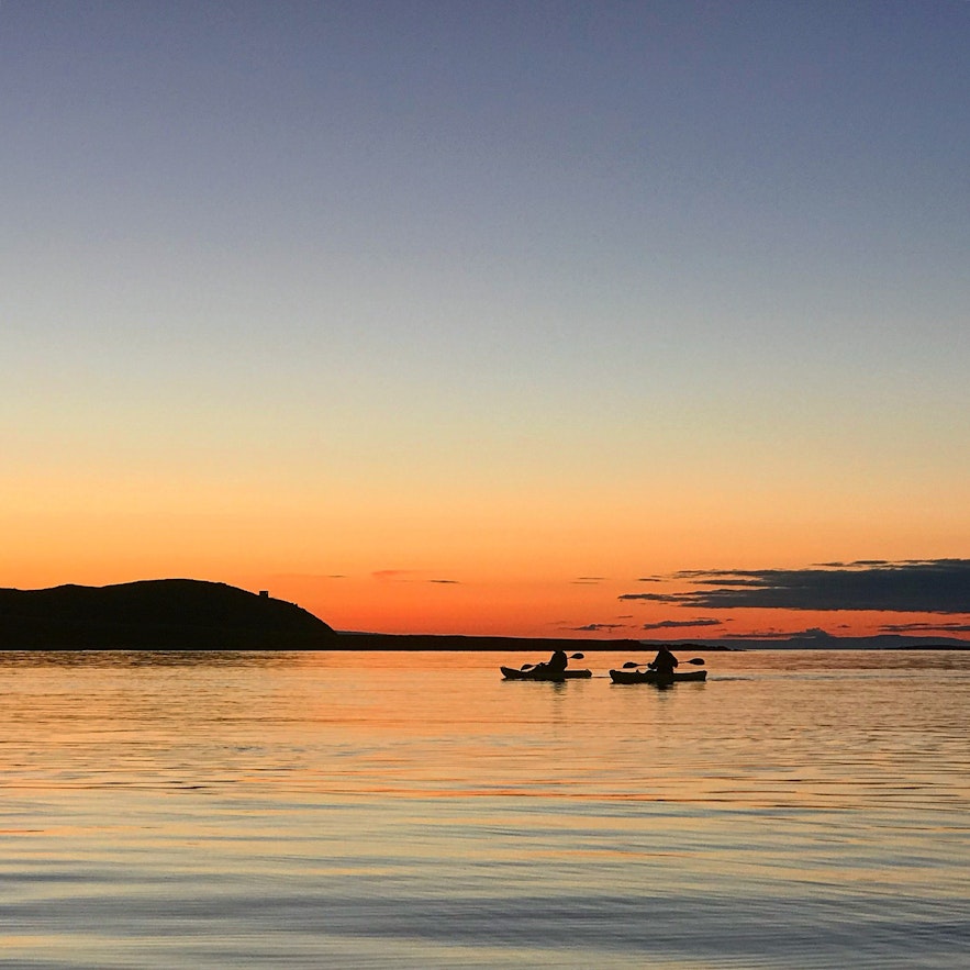 乘皮划艇游弋于午夜阳光照耀下的美丽海面