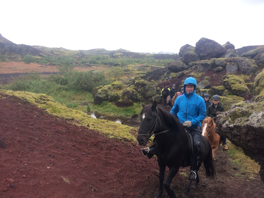 溶岩景観のなかを進む乗馬体験のグループ
