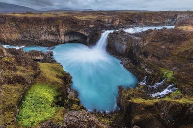 Goðafoss waterfall in summer, with a rainbow arching from it, pictured in north Iceland.