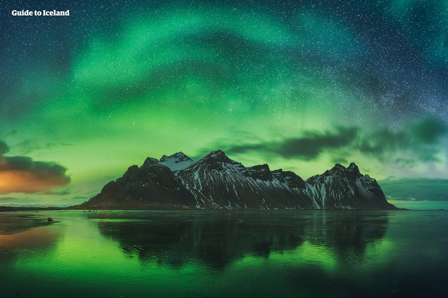 Un hermoso espectáculo de auroras boreales sobre una cordillera de montañas escarpadas de Islandia.