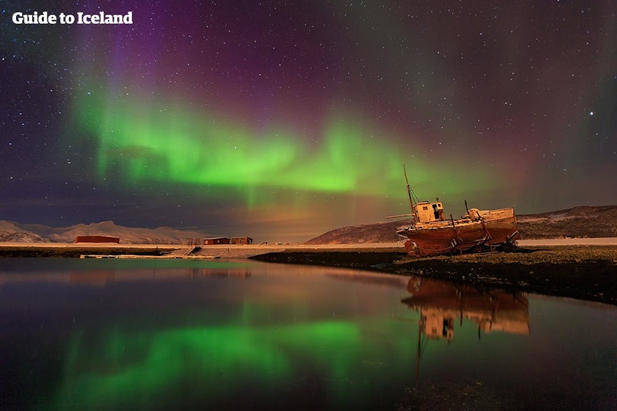アイスランドの西フィヨルド地方の船と、オーロラ