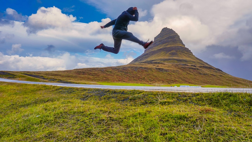 Action shot of man jumping with illusion of foot against mount kirkjufell Iceland