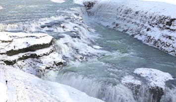 Embark on a snowy journey to witness Gullfoss adorned in winter's icy splendor, a breathtaking scene on the Golden Circle expedition.
