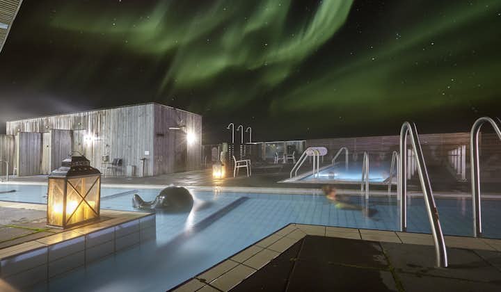 Two of the pools and the sauna at Fontana Geothermal Baths with the northern lights seen overhead.