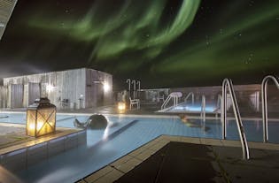 Two of the pools and the sauna at Fontana Geothermal Baths with the northern lights seen overhead.