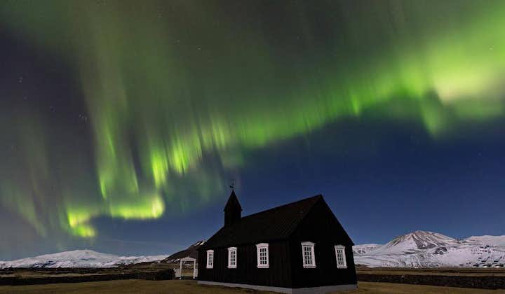 Norrskenet dansar över den kolsvarta kyrkan i Búðir på Snæfellsnes.