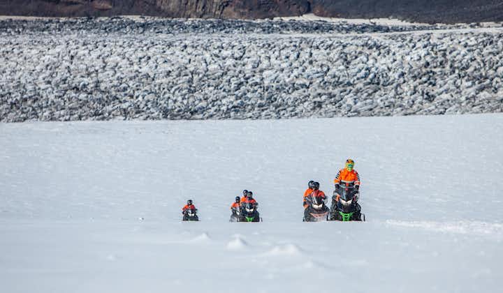People riding snowmobiles across the vast Myrdalsjokull glacier.