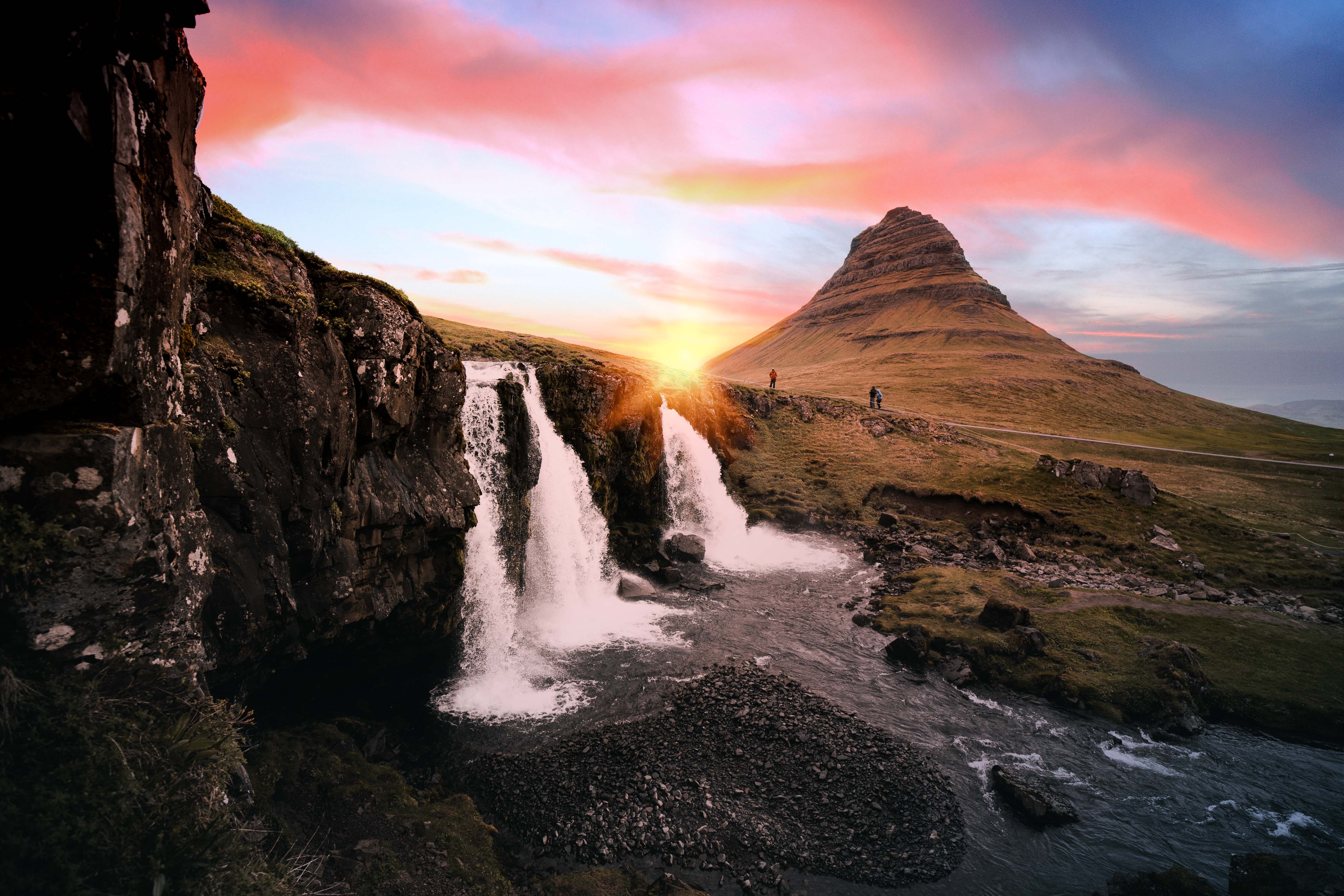 De waterval Kirkjufellsfoss druppelt op de voorgrond terwijl de zon ondergaat