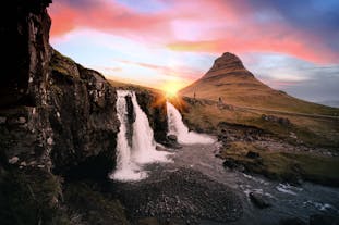 La cascade de Kirkjufellsfoss coule au premier plan au coucher du soleil.