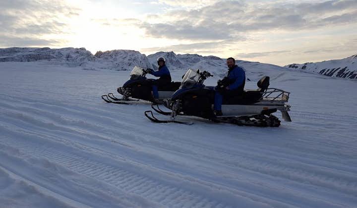 A pair and their snowmobiles under the midnight sun on Vatnajokull glacier.