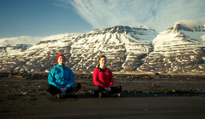 Two woman sitting at the ground while doing yoga in the vastness of Breiddalur valley, near Breiddalsvik.