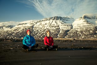 Two woman sitting at the ground while doing yoga in the vastness of Breiddalur valley, near Breiddalsvik.