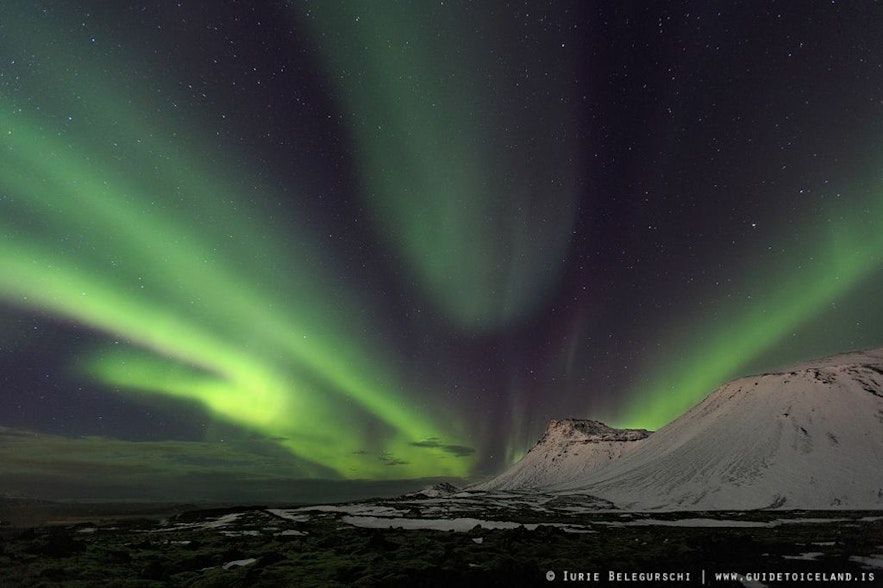 Northern lights over a snowy mountain in Iceland