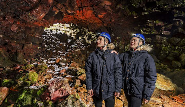Two men wearing blue hard hats stand in the Raufarholshellir lava tunnel.