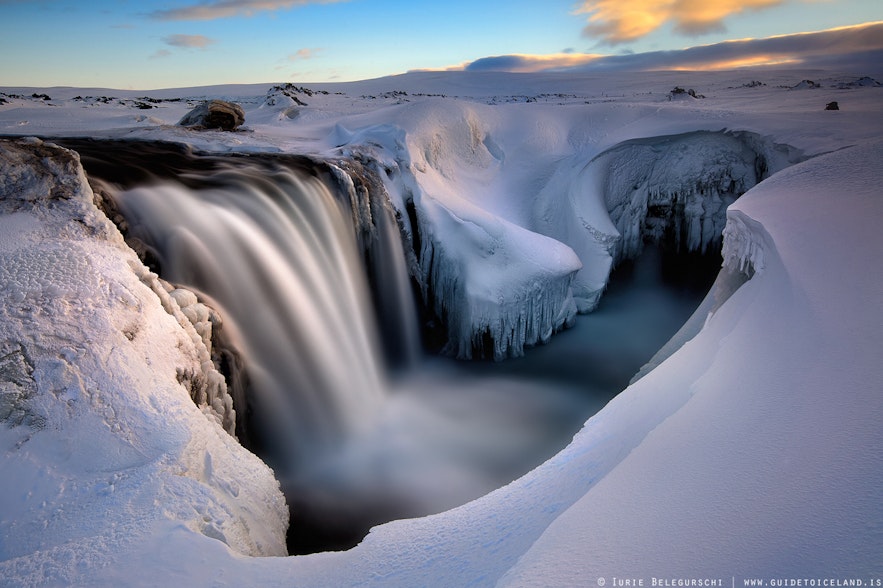 Hrafnabjargafoss waterfall flowing surrounded by snow and ice